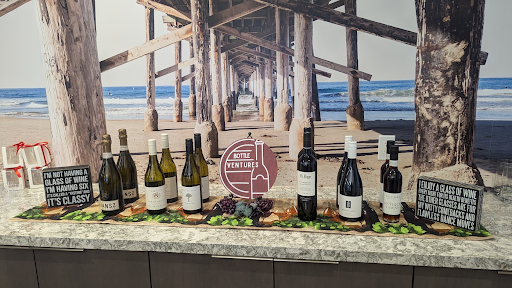 A Bottle Ventures wine lineup with the brand logo sign, set against a Southern California pier backdrop.